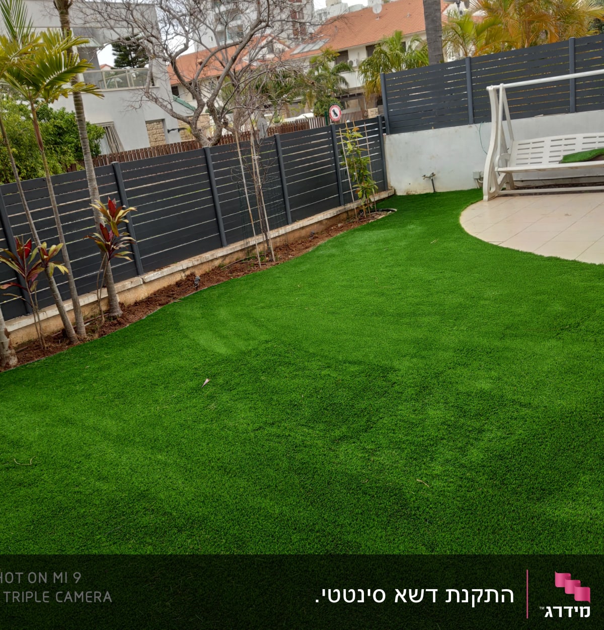 דשא ירוק ועצים בגינה מגודרת